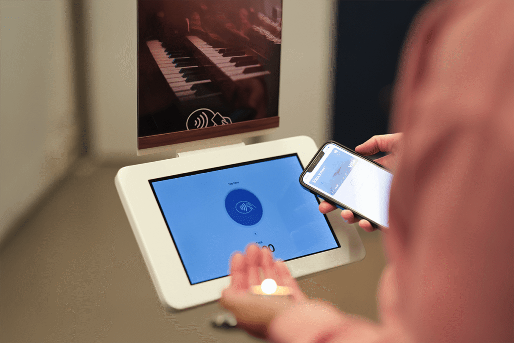 ChurchDesk Terminal som stativ, der en person gir kontaktløst med smarttelefonen